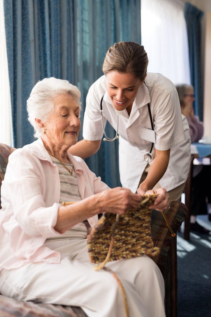 Senior woman showing knitting to female doctor-Palliative care in Hartwell, GA