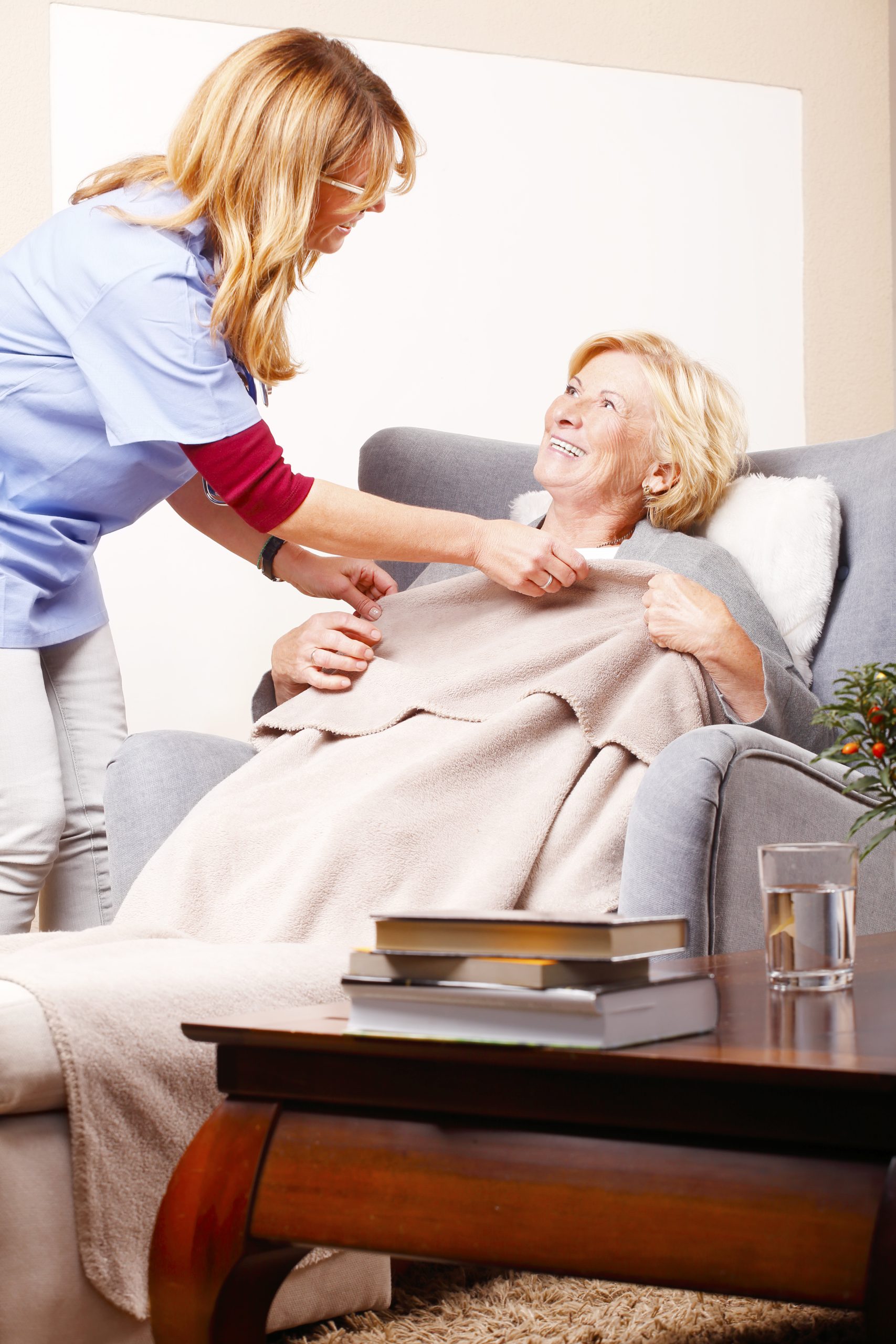 Caregiver assisting a senior woman with a blanket in a comfortable home setting while providing compassionate respite care in Hartwell, GA